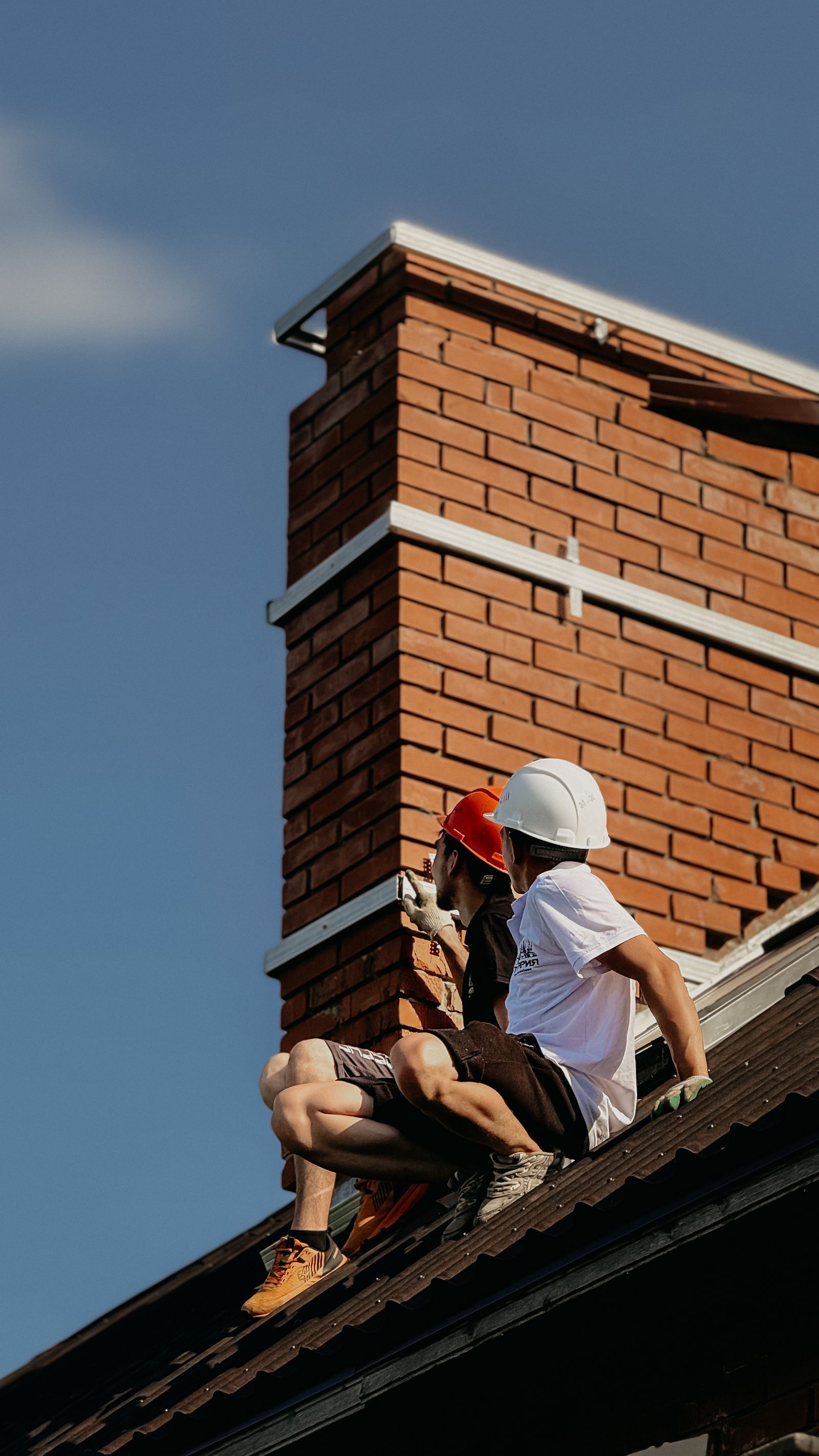 Roofer working beside a brick chimney