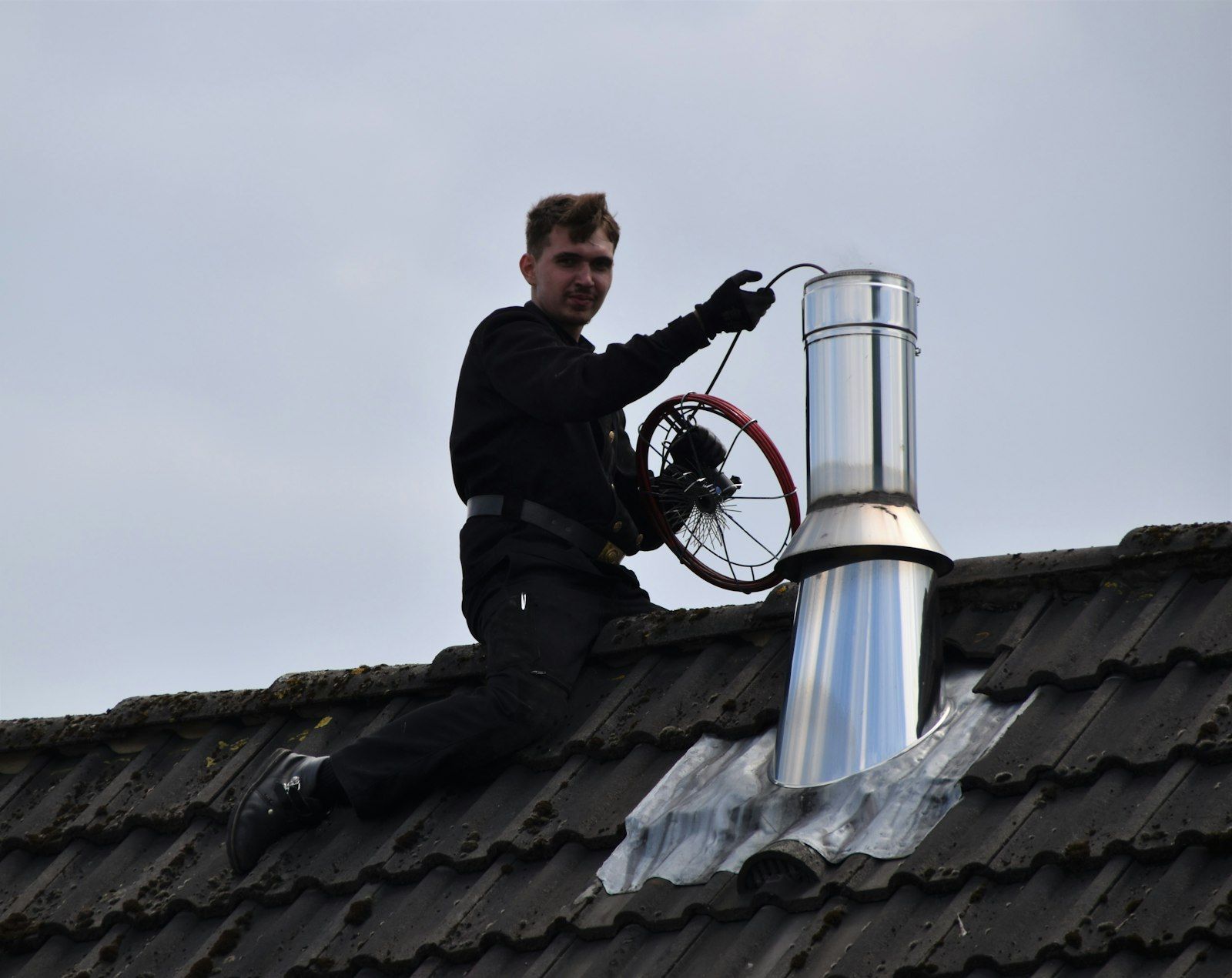 Chimney sweep working the flue with rods