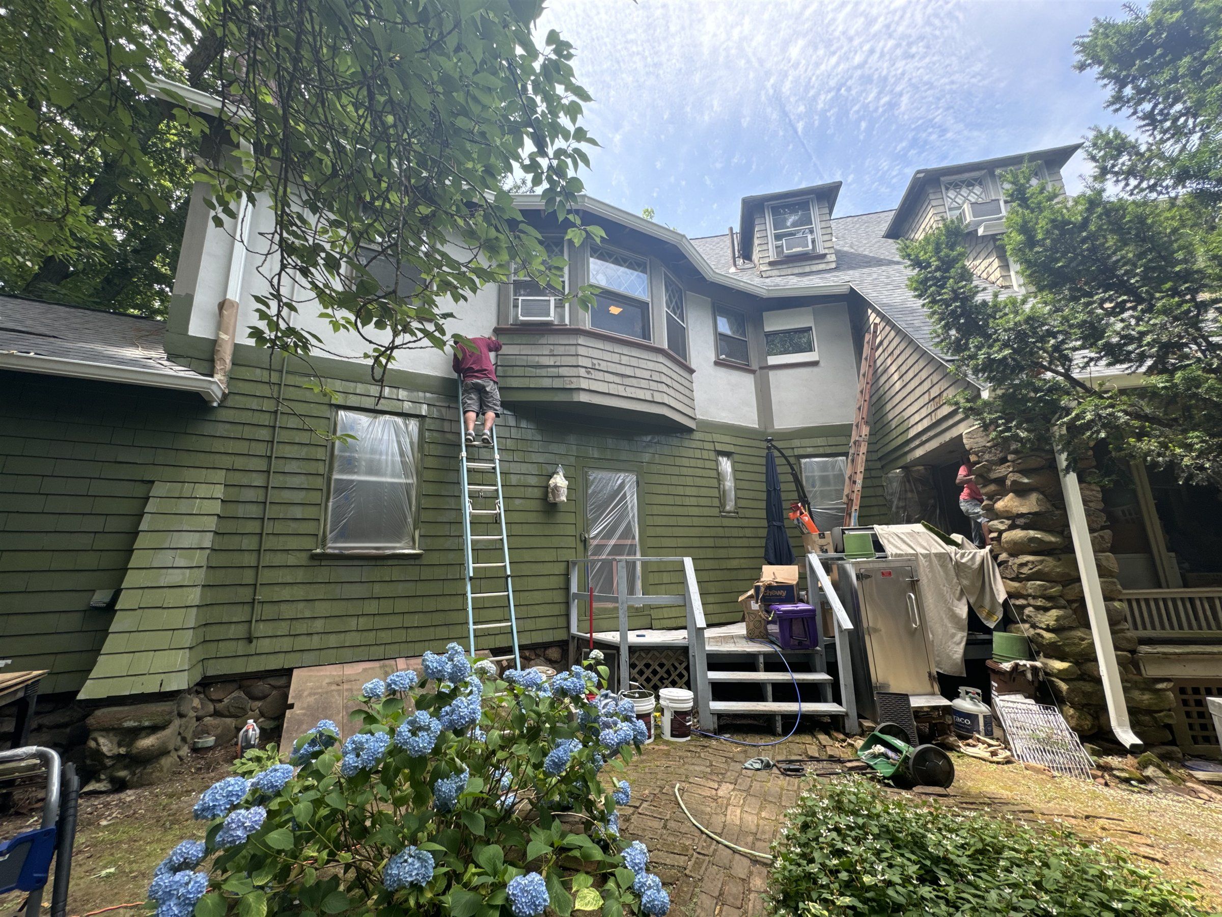 Victorian home getting cedar shake siding, with ladders against the wall