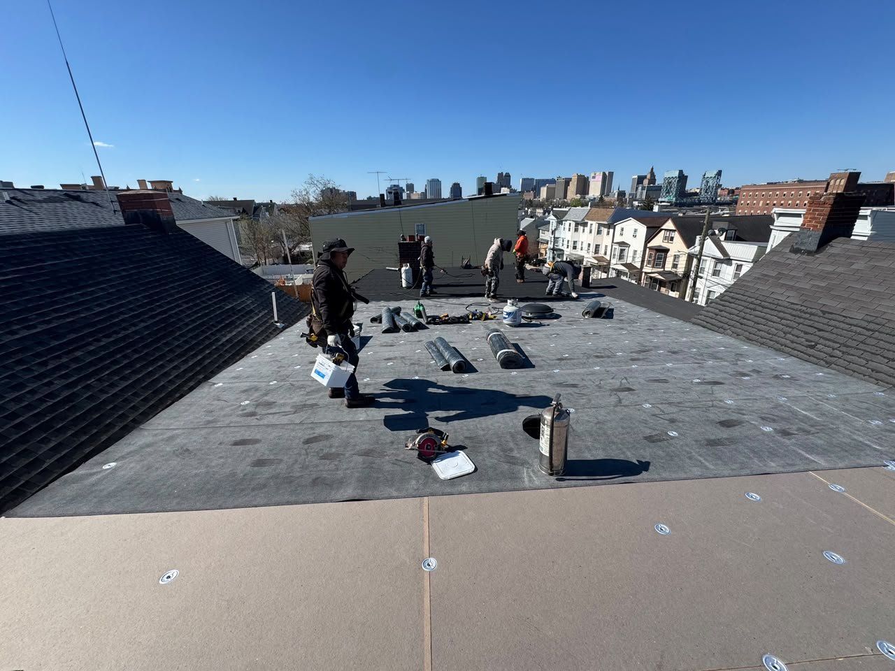 Roofers installing a base sheet and torch-down membrane on a flat roof