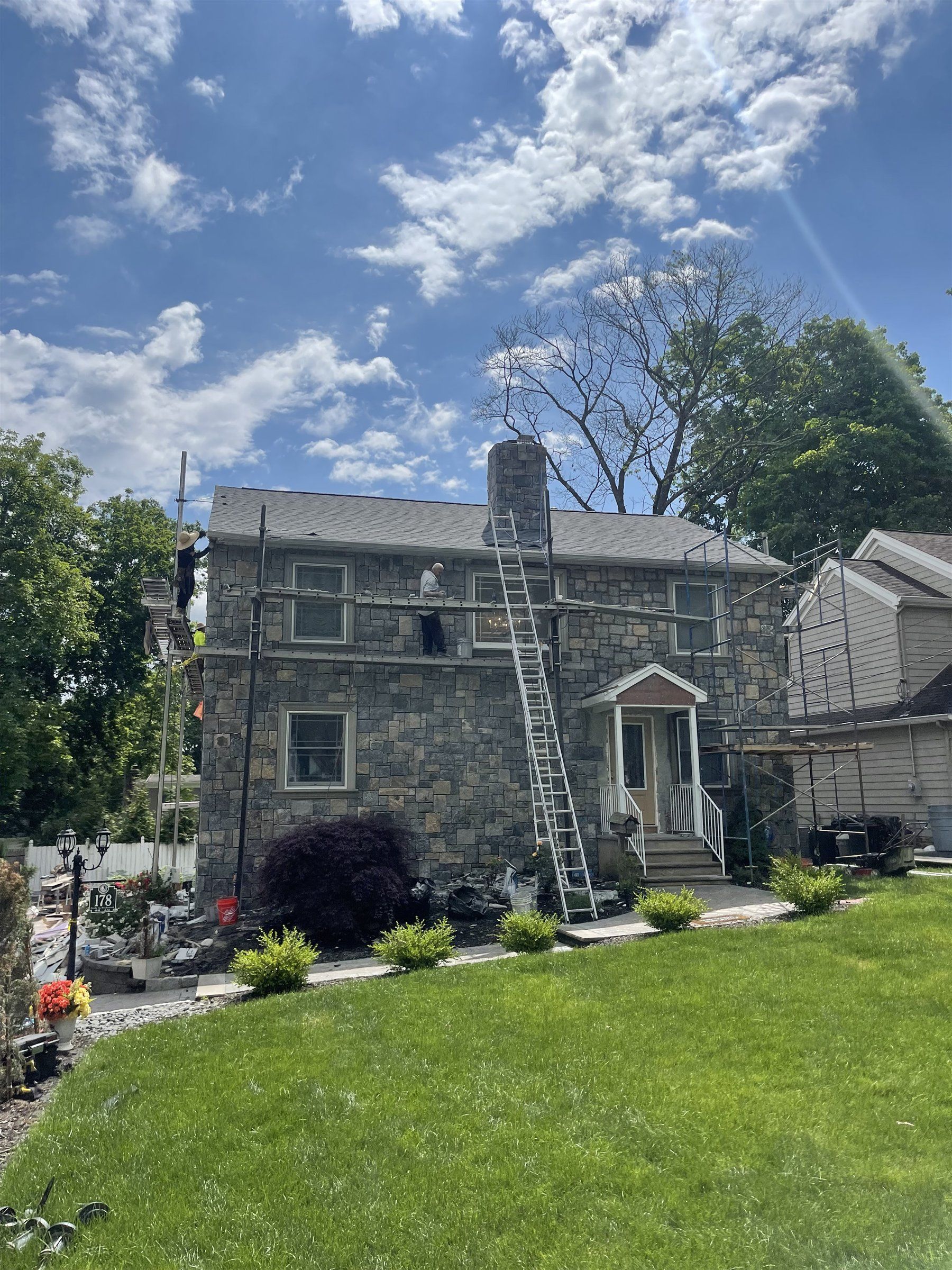 Roofing crew on scaffold at a stone colonial home